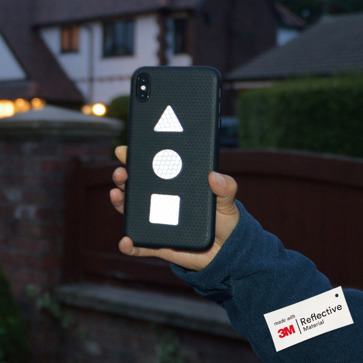 Person holding a Phone case up with 3 White hi vis stickers, triangle, circle and square.